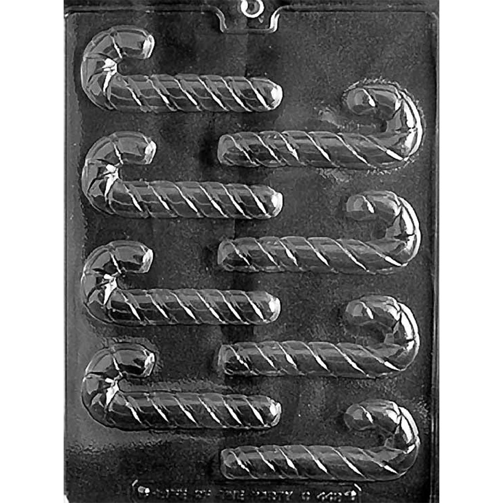 Clear plastic chocolate mold photographed on a dark background with multiple candy cane-shaped cavities featuring curved hooks and spiral twist grooves.