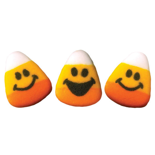 Three candy corn sugar decorations with smiling faces, featuring white, yellow, and orange layers and different cheerful expressions.