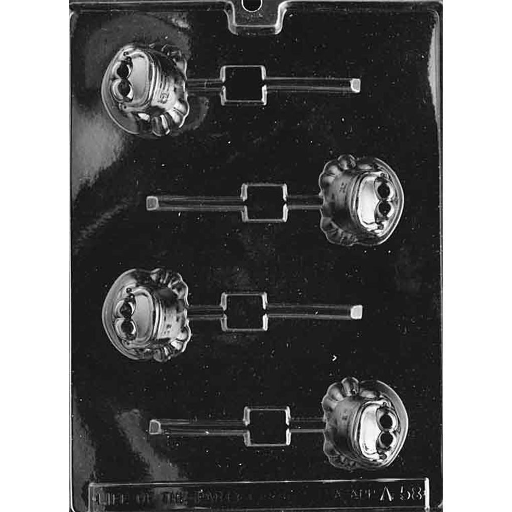 Clear plastic chocolate lollipop mold with four cavities shaped like a plump cartoon frog with bulging eyes and a wide smiling face, each cavity connected to a stick channel on a dark background.