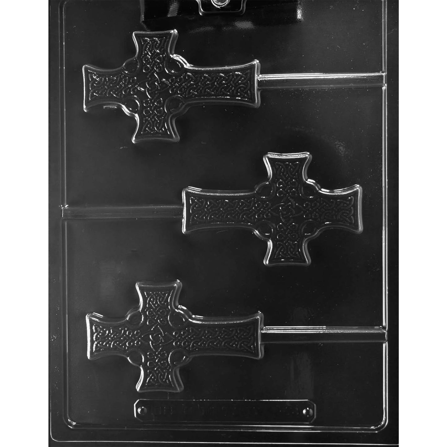 Clear plastic chocolate lollipop mold with three Celtic cross-shaped cavities featuring raised knot-style detail and a circular center, each with a built-in stick channel, shown on a dark background.