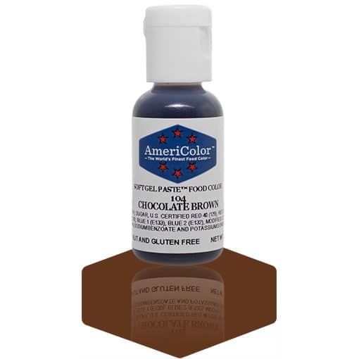 A bottle of AmeriColor Chocolate Brown soft gel paste food coloring, featuring a white cap, blue label with red stars, and placed on a glossy brown surface with its reflection clearly visible.