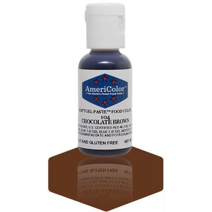 A bottle of AmeriColor Chocolate Brown soft gel paste food coloring, featuring a white cap, blue label with red stars, and placed on a glossy brown surface with its reflection clearly visible.