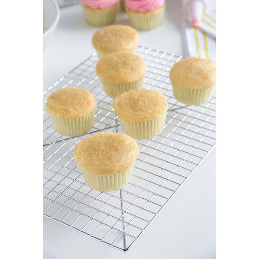 Chrome wire cooling rack holding several freshly baked vanilla cupcakes, showing the raised grid that allows air to circulate beneath baked goods.
