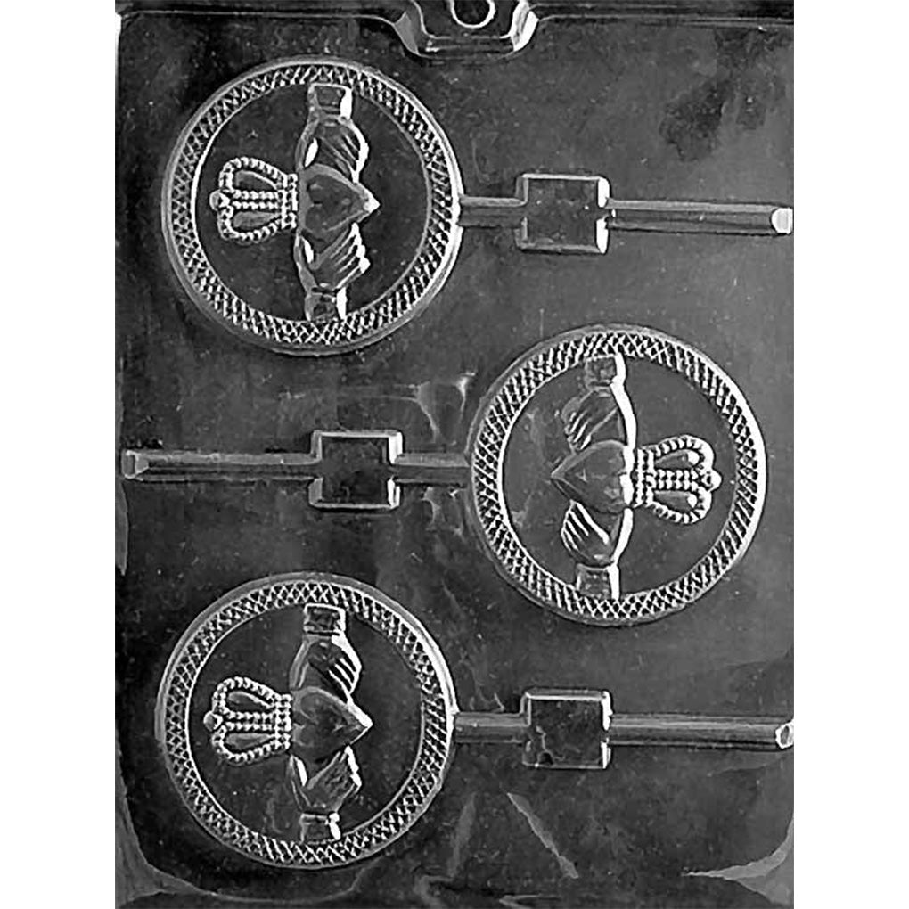 Claddagh chocolate lollipop mold with three round lollipop cavities, each embossed with the Claddagh symbol showing hands holding a heart topped with a crown, plus stick channels, in clear plastic.