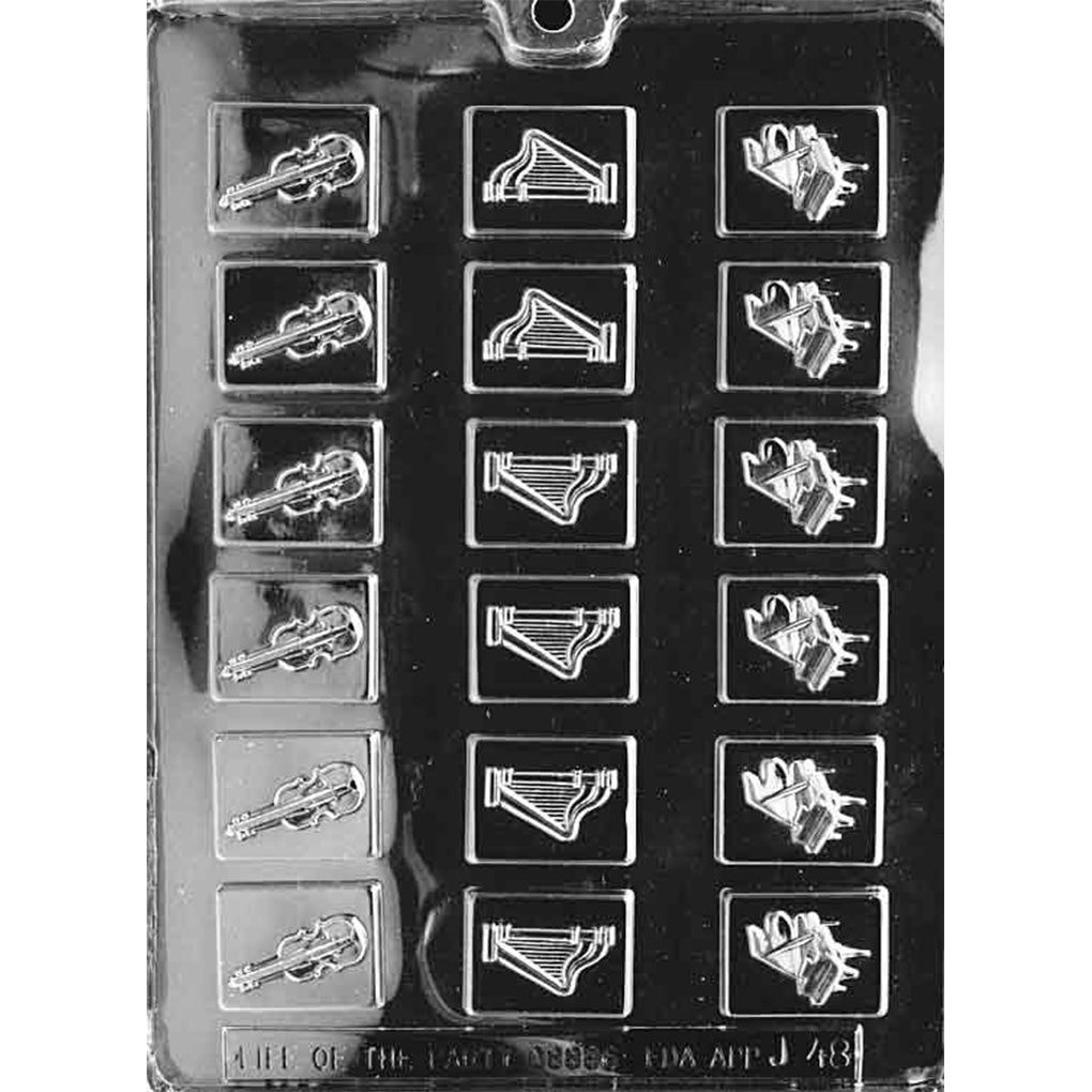 Clear plastic chocolate mold with multiple small rectangular cavities, each embossed with a violin, harp, or grand piano design arranged in three columns.