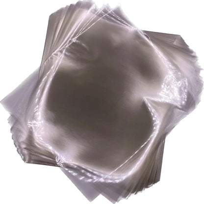 Overlapping stack of clear 4" x 4 ½" cellophane caramel wrappers with smooth, glossy surfaces.