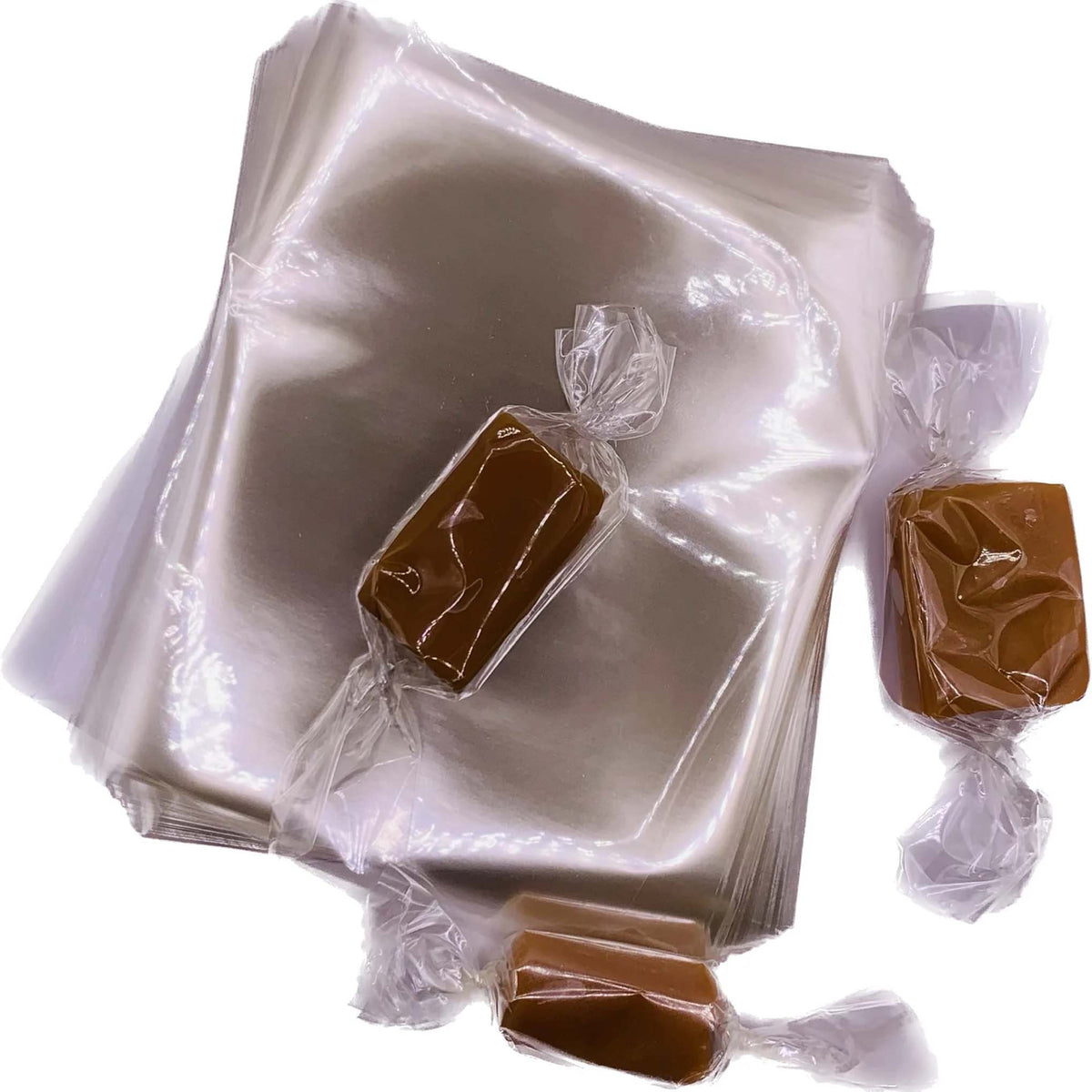 Stack of clear 4" x 4 ½" cellophane caramel wrappers with three rectangular caramel pieces individually wrapped and twisted at both ends.