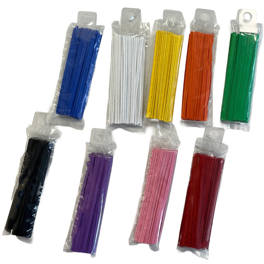 Overhead photo of assorted colored paper twist ties sealed in clear plastic sleeves, including blue, white, yellow, orange, green, black, purple, pink, and red bundles on a white background.