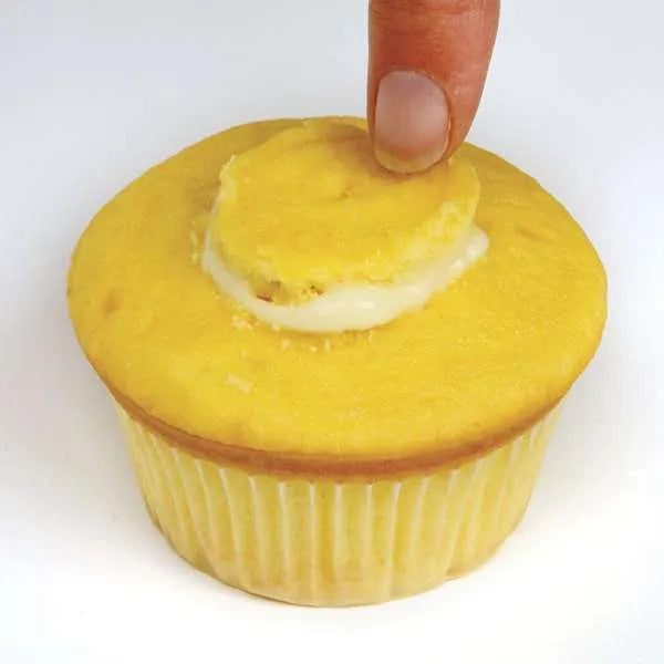 Pressing cupcake top back into place after filling.