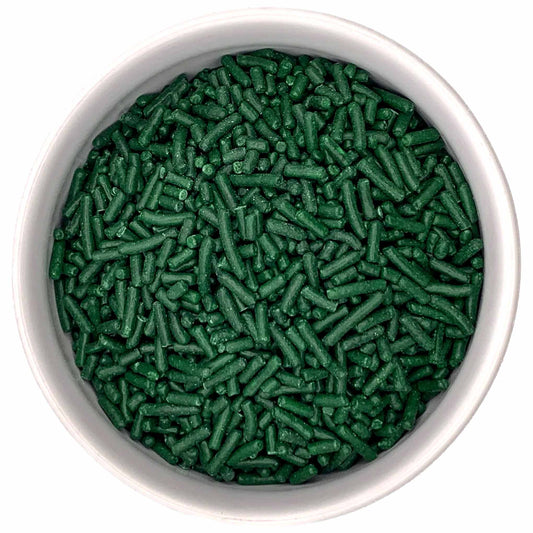 White bowl filled with dark green jimmies sprinkles, showing small cylindrical pieces with a matte finish against a bright white background.