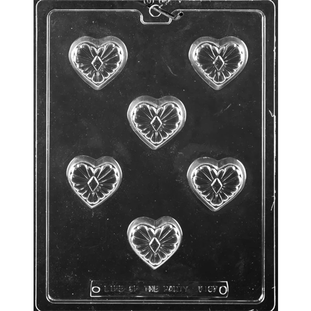 Clear plastic chocolate mold with six deep heart-shaped cavities featuring a raised starburst pattern and a diamond shape in the center for making filled heart chocolates.