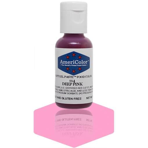 A bottle of AmeriColor Deep Pink soft gel paste food coloring with a white cap and blue label adorned with red stars, standing on a shiny pink reflective surface that mirrors the bottle.