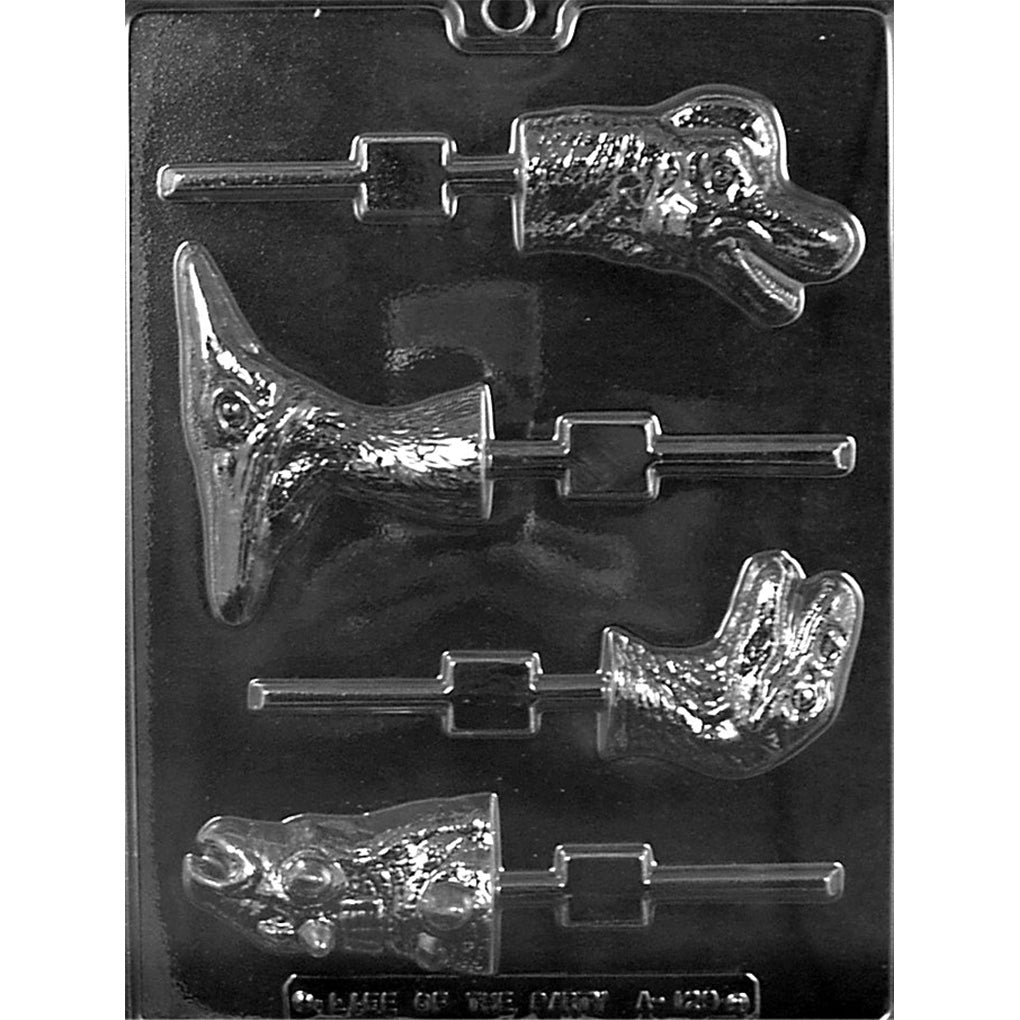 Clear Dinosaur Head Assortment Chocolate Lollipop Mold photographed against a black background with Pterodactyl, Brachiosaurus, Velociraptor, and Ankylosaurus designs and built-in stick channels.