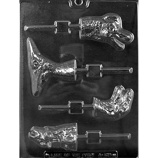 Clear Dinosaur Head Assortment Chocolate Lollipop Mold photographed against a black background with Pterodactyl, Brachiosaurus, Velociraptor, and Ankylosaurus designs and built-in stick channels.