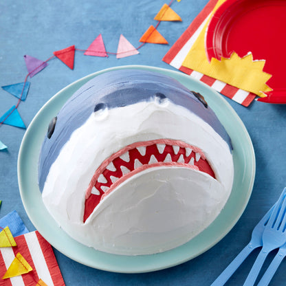 Dome-shaped shark cake with teeth and party decor, made using Wonder Mold Pan.
