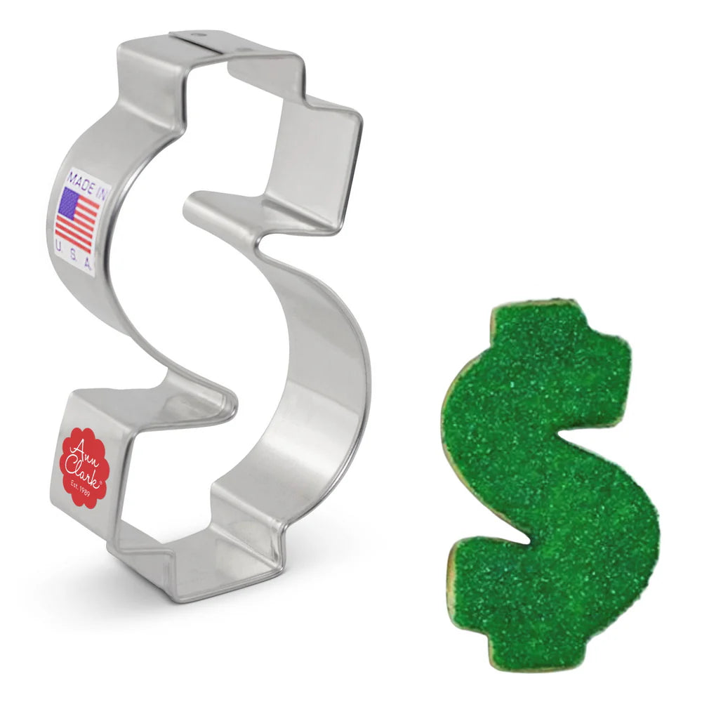 Dollar sign cookie cutter alongside a decorated green sugar cookie in the same shape.