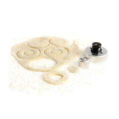 Metal cookie/donut cutter with black handle, surrounded by dough circles.