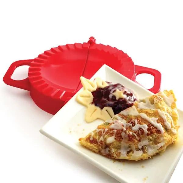 Baked fruit-filled pastry with icing, next to the red dumpling press.