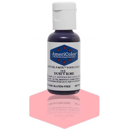 A bottle of AmeriColor Dusty Rose soft gel paste food coloring with a white cap, blue label, and red stars, positioned on a soft dusty rose reflective surface with the bottle’s reflection clearly visible.