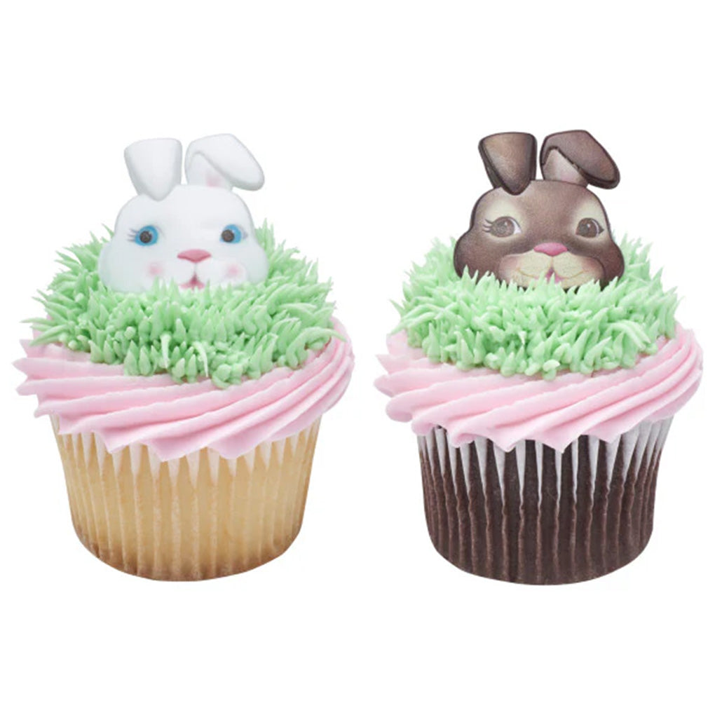 Two cupcakes decorated with pink frosting, green piped grass, and white and brown Easter bunny face rings peeking from the center.