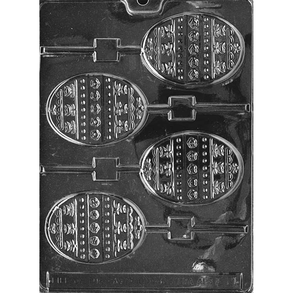 Clear plastic chocolate lollipop mold with four egg-shaped cavities featuring raised striped patterns with dots and small decorative motifs, each connected to a stick channel on a dark background.
