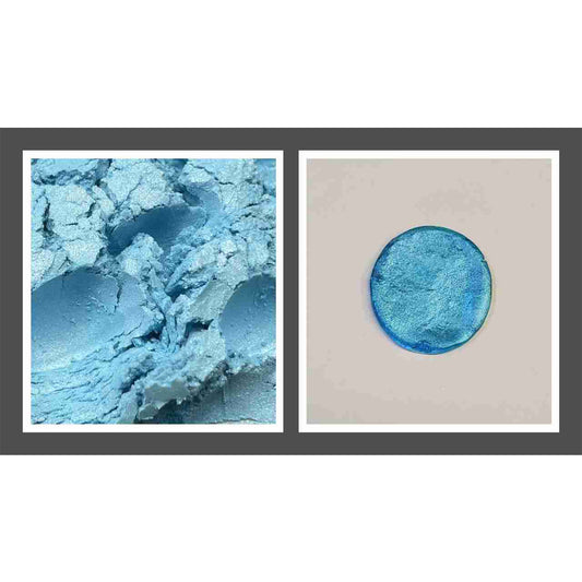 Close-up photo of bright blue edible luster dust powder with a metallic shimmer beside a swatched blue circle showing the reflective finish on a light background.