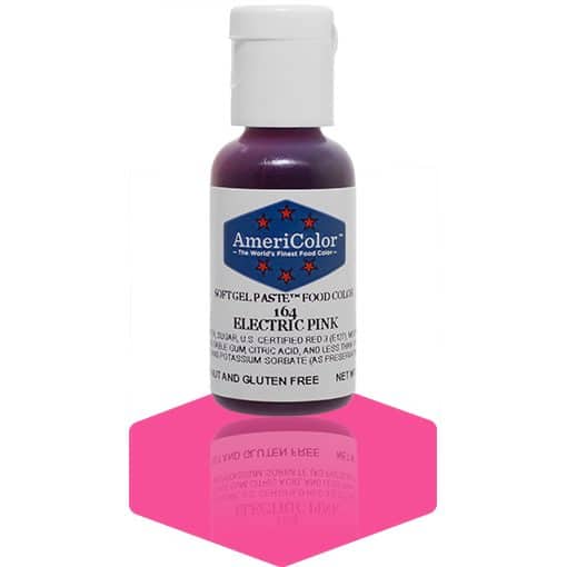 A bottle of AmeriColor Electric Pink soft gel paste food coloring with a white cap, blue label, and red stars, placed on a bright pink reflective surface with the bottle’s reflection visible.