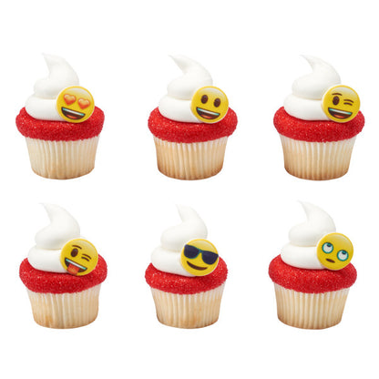 Cupcakes topped with white frosting and red sugar, each featuring a different emoji cupcake ring for party decoration.