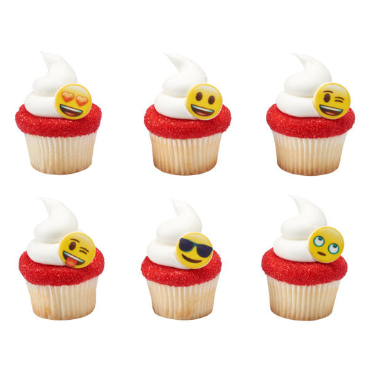 Cupcakes topped with white frosting and red sugar, each featuring a different emoji cupcake ring for party decoration.