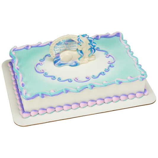 Rectangular cake with whimsical candy-themed graphics, topped by an enchanting unicorn figurine cake decoration, bordered with pastel pink, purple, and turquoise icing.