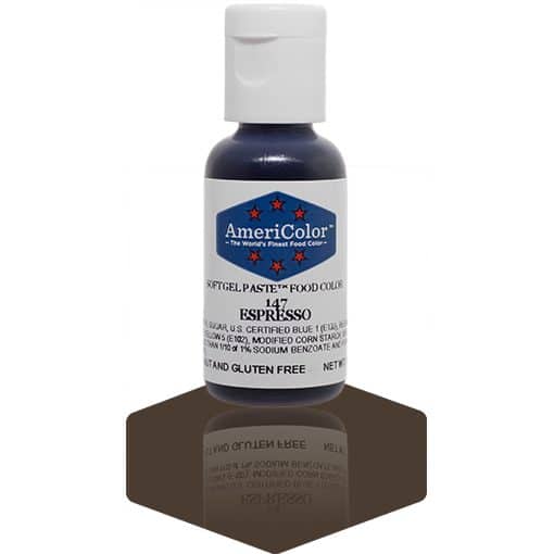 A bottle of AmeriColor Espresso soft gel paste food coloring with a white cap, blue label, and red stars, standing on a dark espresso-brown reflective surface that mirrors the bottle.