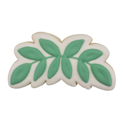 Decorated eucalyptus leaf-shaped cookie with white icing and green leaf details.