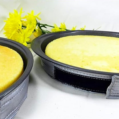 EvenBake cake strips wrapped around round black cake pans filled with yellow cake batter, silver strips secured during baking on a light surface