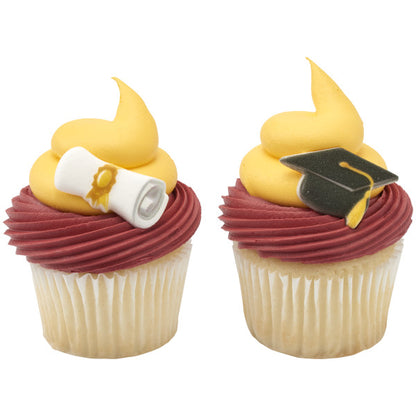 Two cupcakes with maroon and yellow frosting swirls, topped with pressed sugar graduation decorations, one with a diploma scroll and one with a graduation cap.