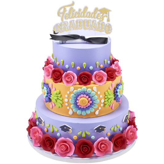 Tall purple tiered cake decorated with colorful piped flowers and roses, topped with a gold Felicidades Graduado topper.