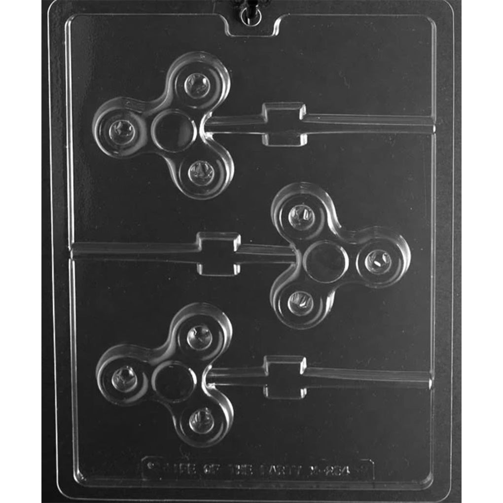 Clear plastic chocolate lollipop mold with three fidget spinner shaped cavities, rounded spinner details, and lollipop stick channels on a dark background.