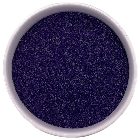 Top-down view of a white bowl filled with purple fine sanding sugar, showing tiny sparkling crystals in a deep violet-purple shade.