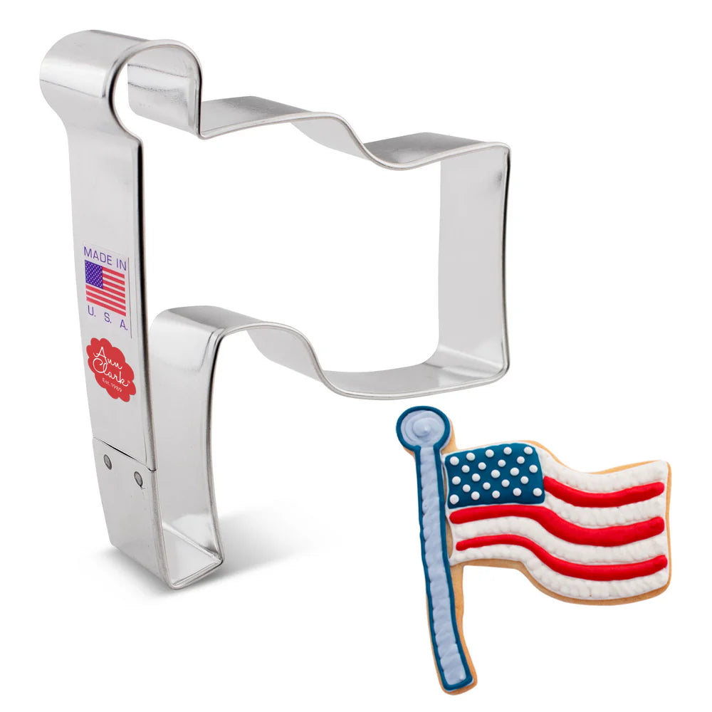 Flag cookie cutter alongside a decorated cookie featuring a red, white, and blue waving flag.