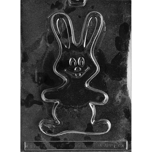 Clear plastic chocolate mold with one large flat smiling bunny shape, tall upright ears, wavy arms, and a cartoon face with buck teeth on a dark background.