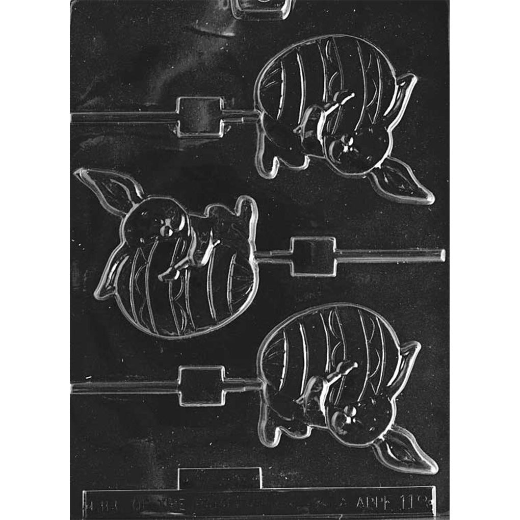 Clear plastic chocolate lollipop mold showing three cavities of a bunny painting a large Easter egg, with recessed lollipop stick channels on a dark background.