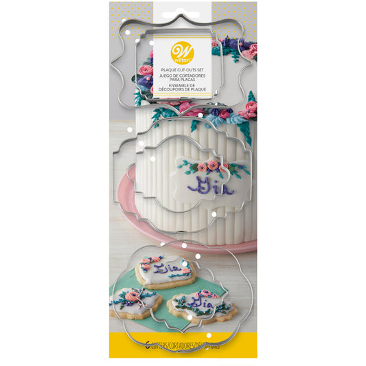 Product packaging showing plaque cutters with decorated cookies and a cake featuring fondant name tags.