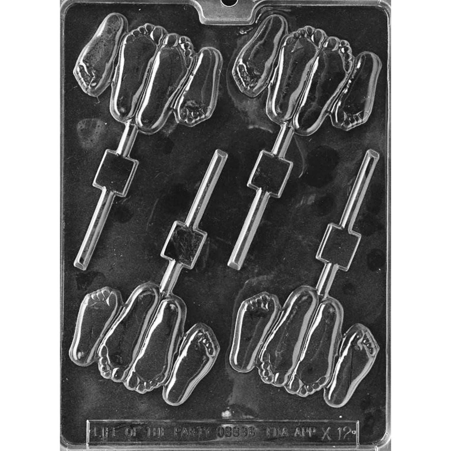 Clear Footsie Chocolate Lollipop Mold photographed against a dark background, featuring four clustered bare-foot cavities with detailed toes, soles, and lollipop stick channels.