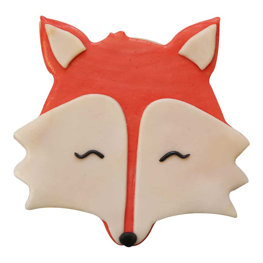 Decorated fox cookie with red and cream icing, featuring closed eyes and a cute nose.