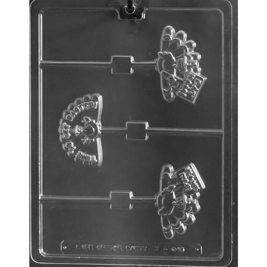 Clear plastic chocolate mold photographed on a dark background with three turkey-shaped cavities; each turkey wears a pilgrim hat and holds a small sign with a humorous saying.