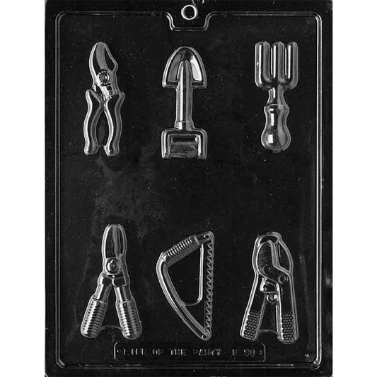 Clear plastic chocolate mold with six gardening tool shapes including pruners, a hand shovel, a three-prong cultivator, a small saw, and clippers.