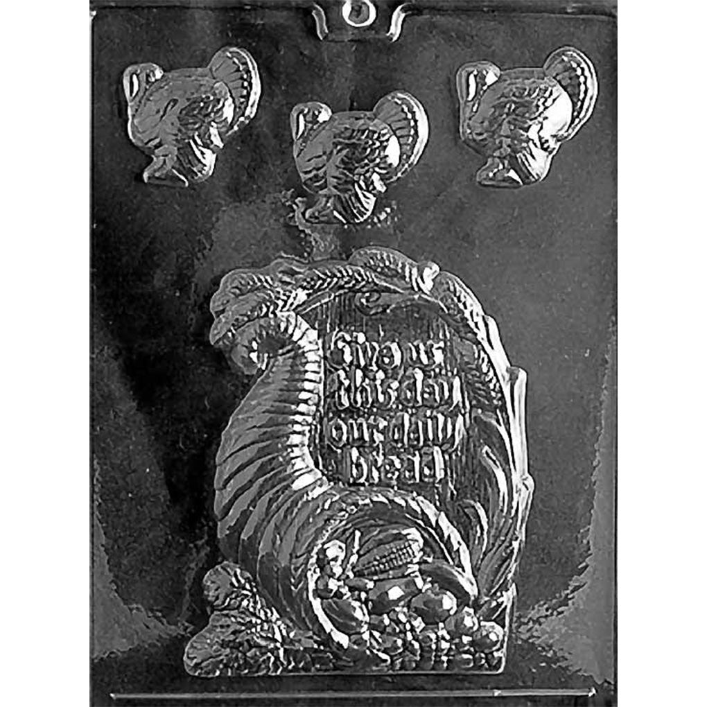 Thanksgiving chocolate mold with one large cornucopia plaque reading “Give Us This Day Our Daily Bread” and three small turkey cavities.

