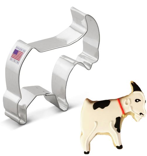 Stainless steel goat-shaped cookie cutter with a "Made in USA" label, accompanied by a decorated goat-shaped cookie with white icing, black spots, and a red collar.