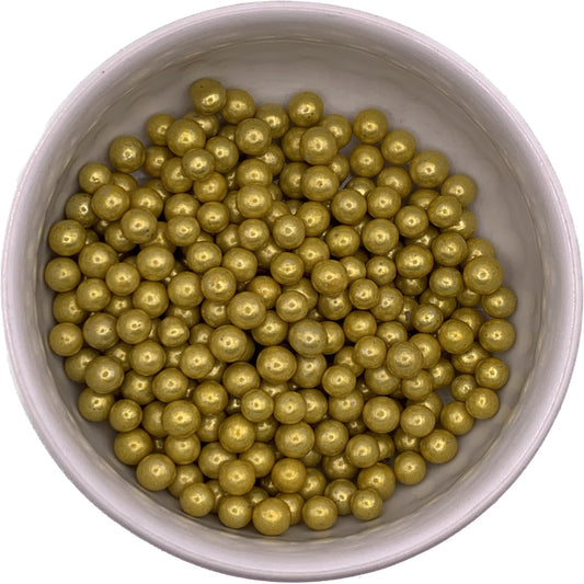 Metallic gold 6mm dragees in a white bowl, used as decorative cake and cookie toppers; non-edible decoration only.