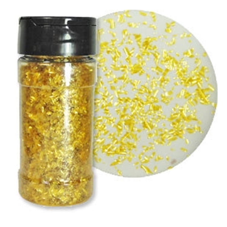 One-ounce bottle of Gold Pearl Edible Glitter Flakes beside a white dessert surface covered with scattered gold flakes