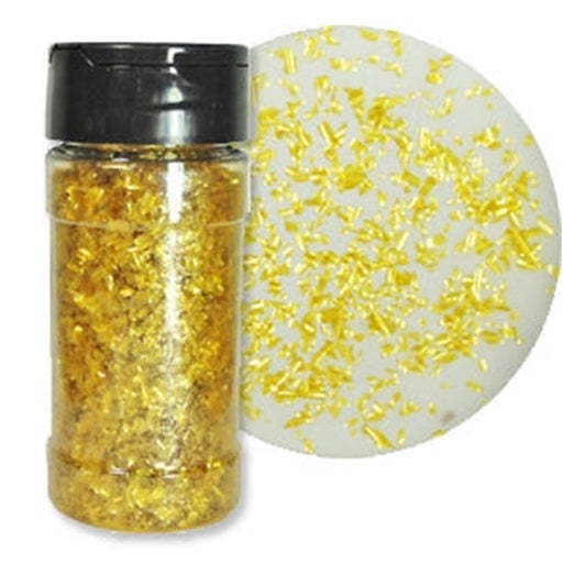 One-ounce bottle of Gold Pearl Edible Glitter Flakes beside a white dessert surface covered with scattered gold flakes